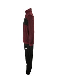 Tuta bordeaux e nera con giacca con zip, colletto alto e polsini elasticizzati, abbinata a pantaloni neri; entrambi hanno dettagli con logo.