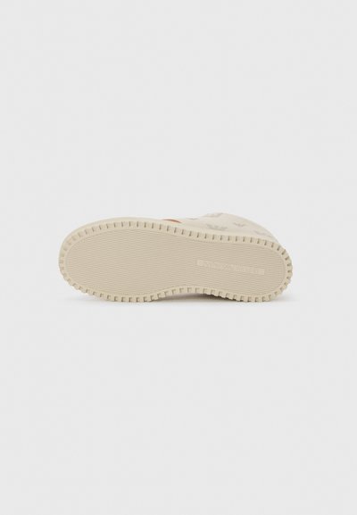 Lysfarvet sneakersål med et struktureret mønster, der har ribbede kanter for bedre greb og minimalistisch branding i midten.