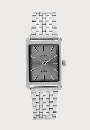 Strieborné hodinky Casio s obdĺžnikovým ciferníkom, kovovým remienkom s článkami, minimalistickými hodinovými značkami a vodotesnosťou do 50 metrov.
