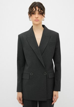 Giacca doppiopetto nera con righe, collo a rever, tasche frontali e bottoni circolari in tonalità argento. Realizzata in tessuto testurizzato.