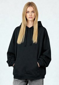 Črna jopa s kapuco iz mehke tkanine, s sprednjim žepom, rebrastimi manšetami in ohlapnim krojem. Gladek otip in minimalističen dizajn.