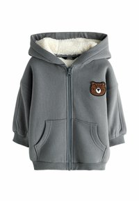 Grå zip-up huvtröja med fleecefoder, stora framfickor och en björnpatch på vänster bröst. Utrustad med dragsko i huvan och elastiska manschetter.