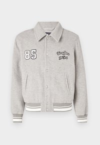 Giacca in misto lana grigia con chiusura a bottoni, loghi ricamati "85" e "Tommy Jeans New York", e polsini e orlo a costine a righe.