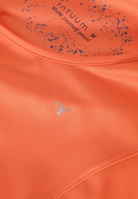 Narančasta sportska majica od glatkog materijala, s srebrnim logotipom i uzorkom prskanja u plavoj boji na unutrašnjem rubu ovratnika.