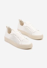 Baskets blanches avec une tige en maille texturée et des côtés lisses. Elles affichent une semelle en caoutchouc beige et des lacets plats. Design minimaliste avec des tirants.