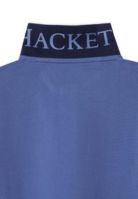 Polo shirt met een blauwe gestructureerde stof en een donkerblauwe kraag met "HACKETT" in lichtblauw gedrukt. De achterzijde onthult stikseldetails.