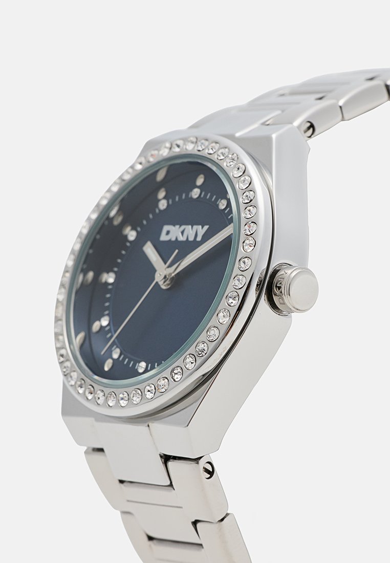 Orologio da polso argento con quadrante blu scuro, accenti di cristallo e bracciale in acciaio inossidabile. Presenta una cassa rotonda e indicatori delle ore semplici.