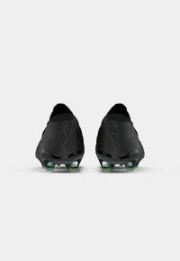 Pair of black soccer cleats shown from the heel, featuring green-tipped studs and "FUTURE" branding on the back.