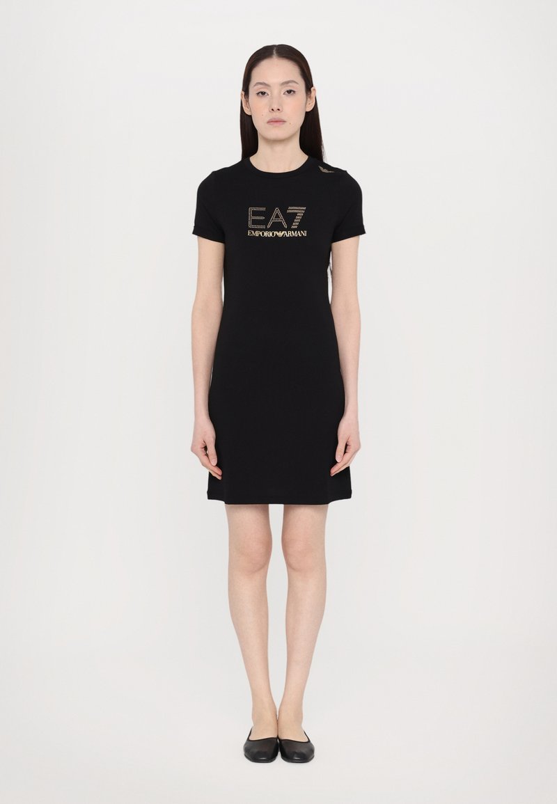 Μαύρο φόρεμα κοντομάνικο με λογότυπο "EA7 Emporio Armani" σε χρυσό. Φτιαγμένο από μαλακό ύφασμα, διαθέτει εφαρμοστή γραμμή και μήκος μέχρι το γόνατο.