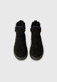 Černé semišové kotníkové boty s měkkým černým kožichem. Jednoduchý slip-on design s kulatou špičkou a texturovanou gumovou podrážkou.
