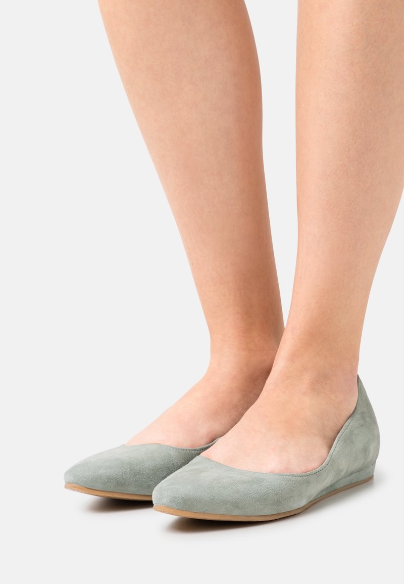 Ballere verde in suede con punta affusolata e tacco basso a cuneo. Tessuto liscio senza motivi visibili o accessori. Design semplice e minimalista.