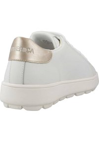 Sneaker bianca con tomaia in pelle liscia e collare imbottito. Presenta un accento dorato metallico sul tallone e una suola in gomma testurizzata.