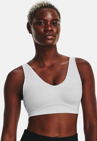 Sutiã desportivo branco com uma textura suave, apresenta um decote em V e alças largas, concebido para conforto e apoio. Sem detalhes de hardware visíveis.