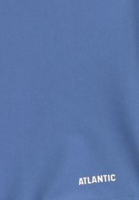 Niebieska tkanina o gładkiej fakturze z białym logo "ATLANTIC" w dolnym rogu.