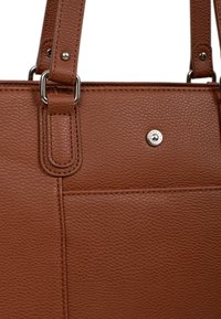 Bruine handtas van textuurleer met een gladde afwerking, voorzien van metalen hardware, een drukknoopdetail en verstelbare schouderbanden.