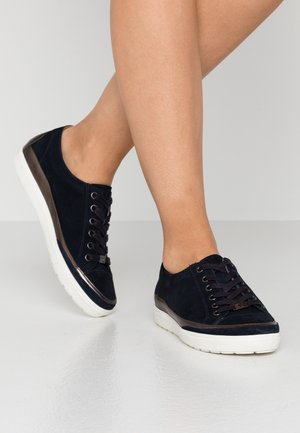 Navy suede sneakers with brown leather accents, round toe, flat white sole, and lace-up design. Texture appears soft with a glossy finish.