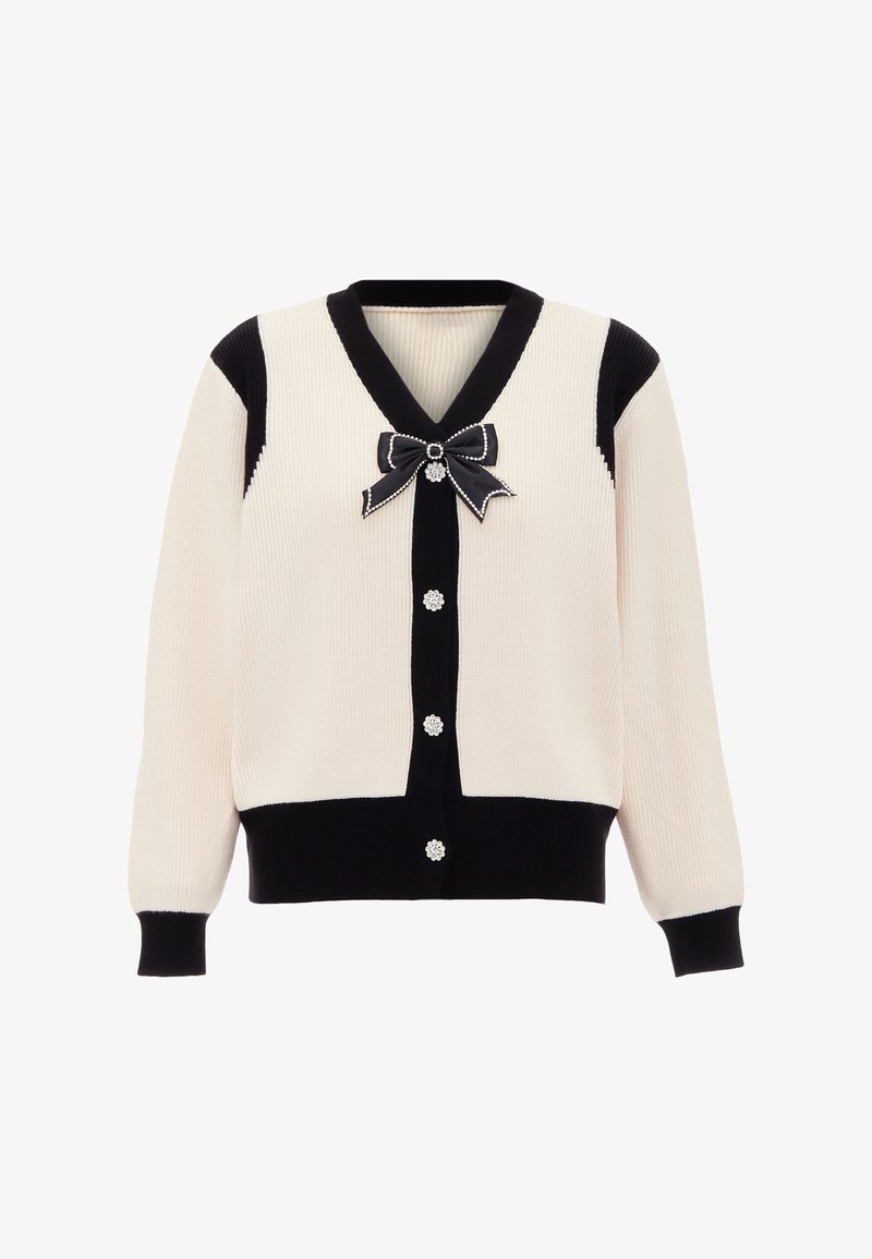 Kremowy i czarny kardigan o prążkowanym wzorze z dekoltem w serek, z guzikami przypominającymi perły oraz czarną kokardą przy kołnierzu. Miękka tekstura z kontrastującymi kolorami.