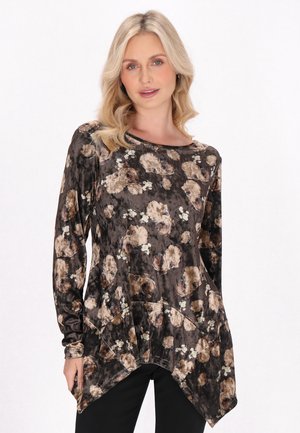Langærmet top i mørkebrun fløjl med et blomstermønster i beige og hvid. Har en afslappet pasform og asymmetrisk kantdesign.