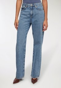 Jasnoniebieskie dżinsy z wysokim stanem o prostym kroju, wykonane z denimu. Zamek błyskawiczny i guzik z przodu, z kieszeniami z przodu i z tyłu.