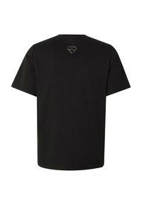 Μαύρο κοντομάνικο T-shirt που φαίνεται από πίσω με ένα μικρό διαμαντένιο λογότυπο κοντά στη λαιμόκοψη.