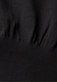 Tessuto nero lavorato a maglia con un motivo testurizzato e dettagli arricciati lungo il bordo, che mostra una consistenza complessiva liscia e morbida.