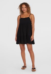 Robe noire sans manches avec un décolleté carré, jupe froncée et ourlet volanté. Tissu doux et bretelles spaghetti ajustables.
