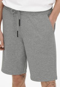 Pantaloni corti grigi in cotone con vita elasticizzata, chiusura con lacci e tasche laterali; texture liscia con un design casual.