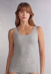 Grå linne gjort av ribbat tyg. Har en rundad halsringning och breda axelremmar, vilket ger en åtsittande passform och mjuk textur.