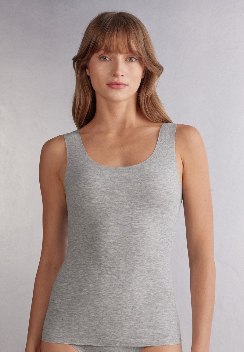 Grå linne gjort av ribbat tyg. Har en rundad halsringning och breda axelremmar, vilket ger en åtsittande passform och mjuk textur.