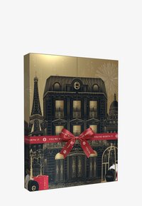 Goldene Geschenkbox mit Illustration eines Pariser Gebäudes und dem Eiffelturm. Geschmückt mit einer roten Schleife und dem Text „DU BIST ES WERT“.