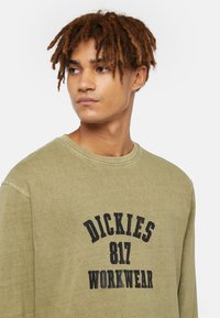 Olive green long-sleeve shirt made of cotton, featuring a round neckline and bold black text: "DICKIES 817 WORKWEAR" on the front.