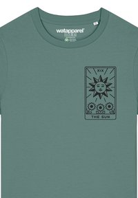 Groene t-shirt met korte mouwen en een ronde hals. Heeft een zwart tarotkaartontwerp met een zon en bloemen. Zachte stofstructuur.