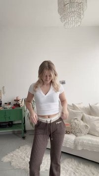 White v-neck t-shirt and brown patterned sweatpants with an elastic waistband. Notable details include drawstrings and logo on pants.