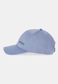 Gorra de béisbol azul claro con visera curva y el logo "GUESS" bordado en el lateral, mostrada sobre un fondo liso.