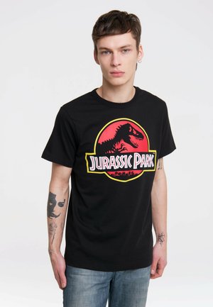 Camiseta de algodón negra con un gran logo de Jurassic Park en rojo y amarillo, con la silueta de un dinosaurio. Mangas cortas y cuello redondo.