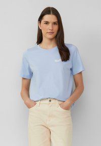 T-shirt en coton bleu clair avec des manches courtes et un col rond, arborant le mot "HAPPY" en blanc sur la poitrine gauche.