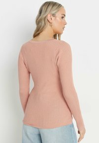 Långärmad, ribbad topp i mjuk rosa, tillverkad av stretchigt material. Har en rundad halsringning och en figurnära siluett, med en något ventilerad nederkant.