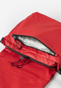 Borsa di tessuto rossa con una superficie liscia, dotata di chiusura a cerniera, doppie linguette e una fodera interna di colore grigio chiaro.