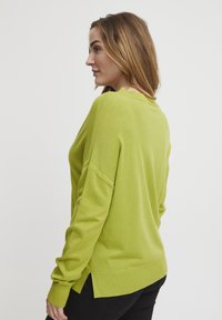 Grüner gestrickter Pullover mit langen Ärmeln, einem runden Ausschnitt und lockerer Passform. Verfügt über seitliche Schlitze am Saum für zusätzlichen details.