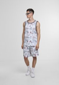 Sett med herre-tanktop og shorts med et flytende, abstrakt mønster i lyse farger, laget av lett stoff; avsluttet med kontrasterende kant.
