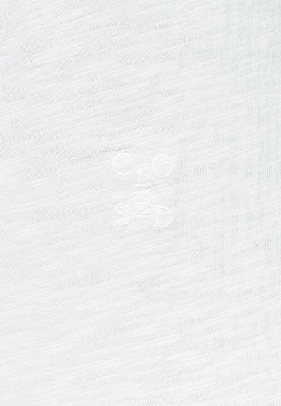 Tissu blanc texturé avec une broderie subtile en relief formant des lettres stylisées "C", "I", "O", "S" et "D".