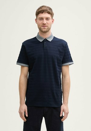 Marineblaues Poloshirt mit strukturierten Streifen, grauen Kragen- und Ärmelakzenten, mit drei Knöpfen. Hergestellt aus einem weichen, atmungsaktiven Material.