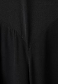 Tela de vestido negra, textura suave con un brillo sutil. Presenta un diseño abstracto de costura y frunces en los bordes para un detalle adicional.