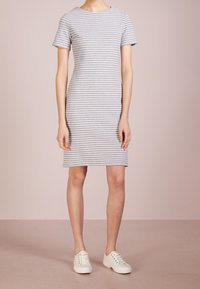 Robe à manches courtes à rayures grises et blanches, coupe ajustée, longueur genou, fabriquée en tissu léger, associée à des baskets blanches.