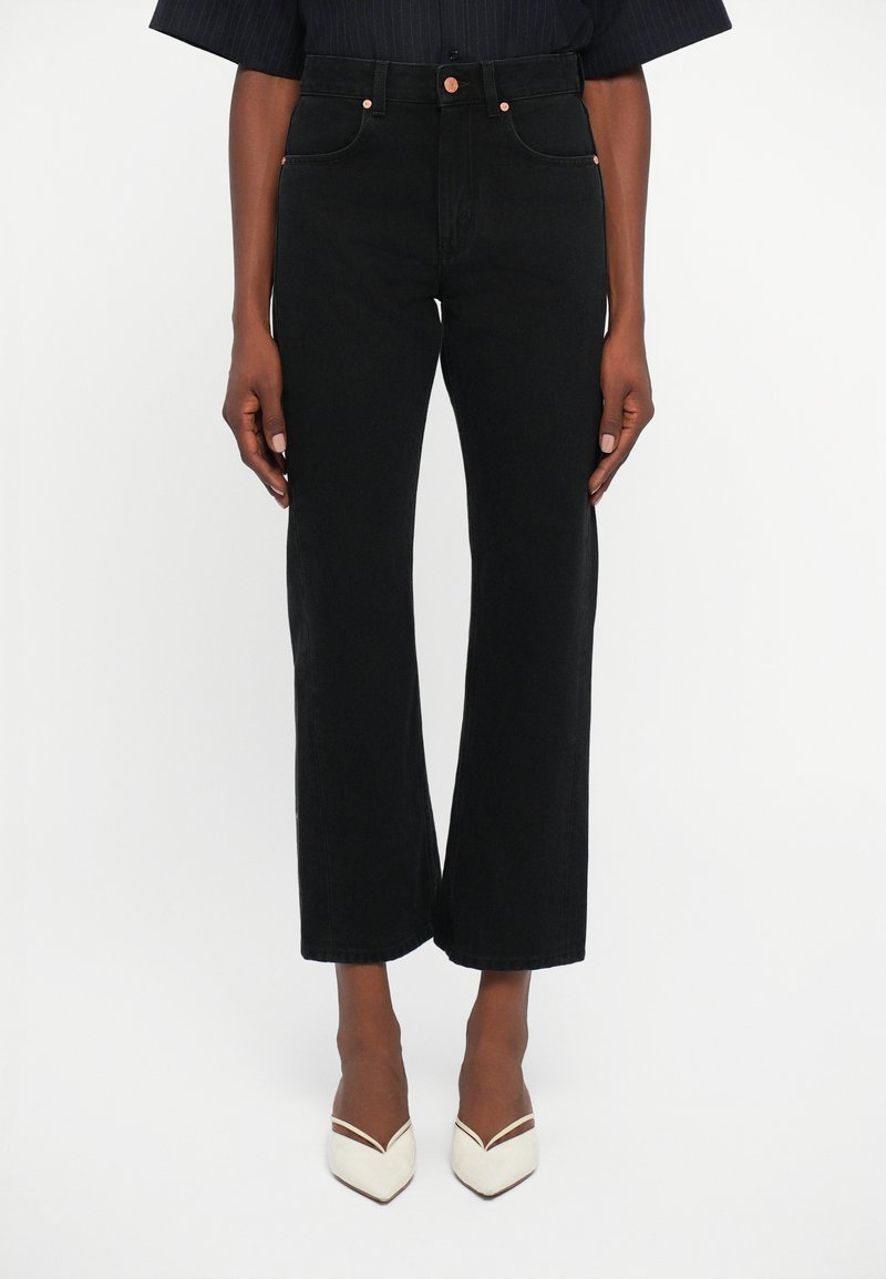 Jeans en denim noir taille haute avec une coupe droite, ornés de boutons en cuivre et d'un design classique à quatre poches.