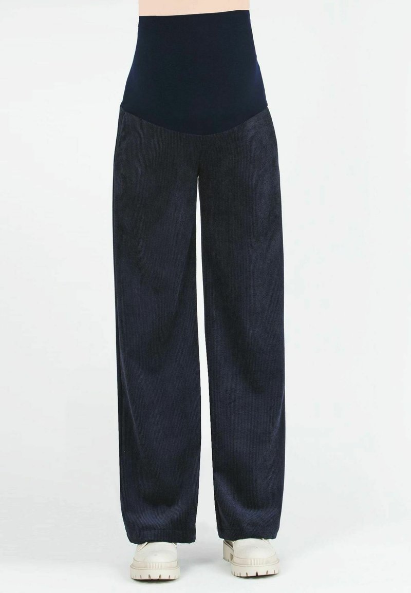 Pantaloni a gamba larga in corduroy blu marina con una vita alta. Texture morbida e motivo a coste. Abbinati a sneakers di colore chiaro.