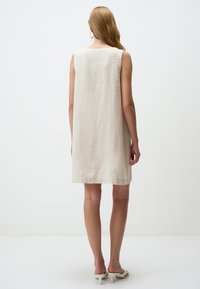 Cremefarbenes ärmelloses Leinenkleid mit geradem Schnitt, subtiler Textur und einem Saum, der oberhalb des Knies endet. Einfaches Design, keine Muster.