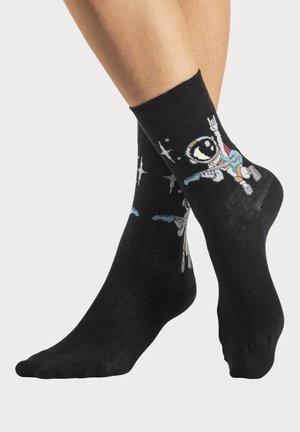 Schwarze Baumwollsocken mit einem lebhaften Astronauten-Design, der vor einem sternenübersäten Hintergrund mit bunten Details Gitarre spielt.