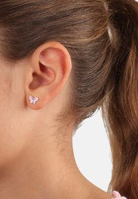 Orecchini a forma di farfalla, di piccole dimensioni, nei toni del rosa e dell'argento, con dettagli delicati e un design semplice con perno, indossati all'orecchio.