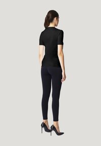 Haut noir à manches courtes associé à des leggings noirs, doté d'un design ajusté et d'une texture lisse, complété par des talons hauts noirs.